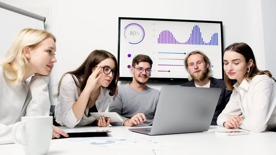 A group of professionals engaged in a business meeting with a presentation in a modern office.