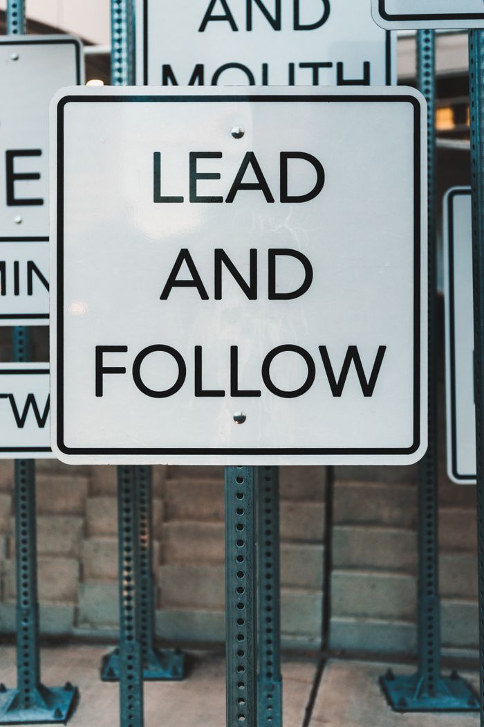 Photo of urban signage displaying Lead and Follow, emphasizing guidance and navigation.